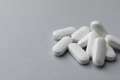 Photo of Pile of calcium supplement pills on light grey background, closeup. Space for text