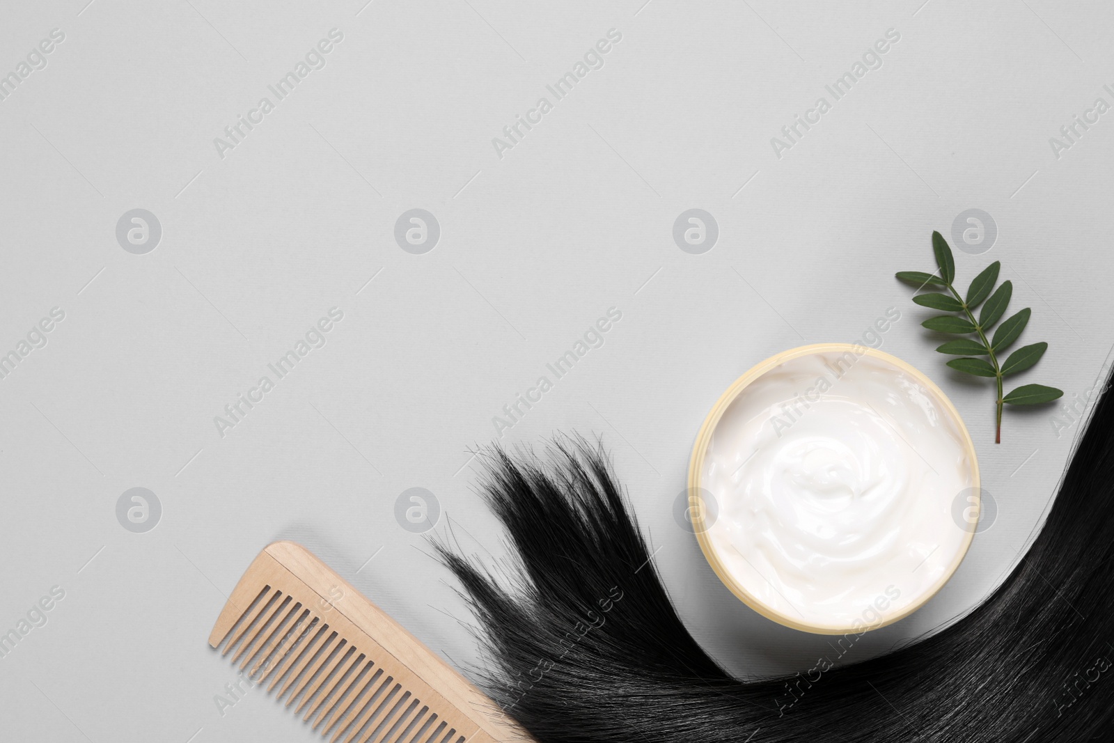 Photo of Flat lay composition with lock of healthy black hair on light grey background. Space for text