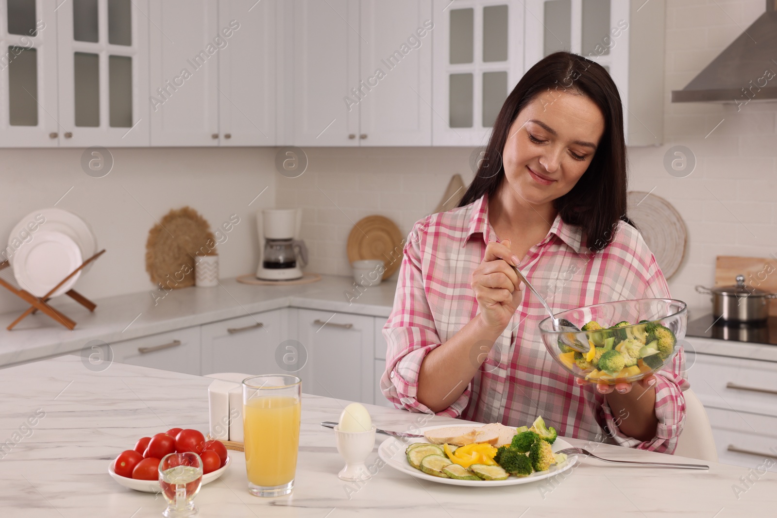 Photo of Beautiful overweight woman having healthy meal at table in kitchen