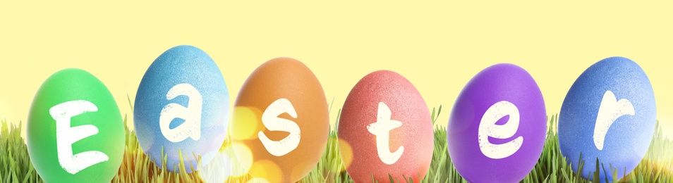 Image of Happy Easter. Colorful dyed eggs on green grass against yellow background, banner design