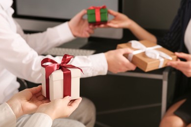 Photo of Colleagues presenting gifts each other in office, closeup. Space for text