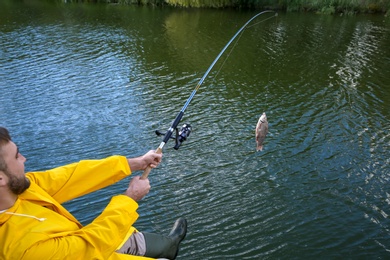 Photo of Man with rod fishing at riverside. Recreational activity