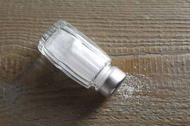 Photo of Organic salt in glass shaker on wooden table, top view