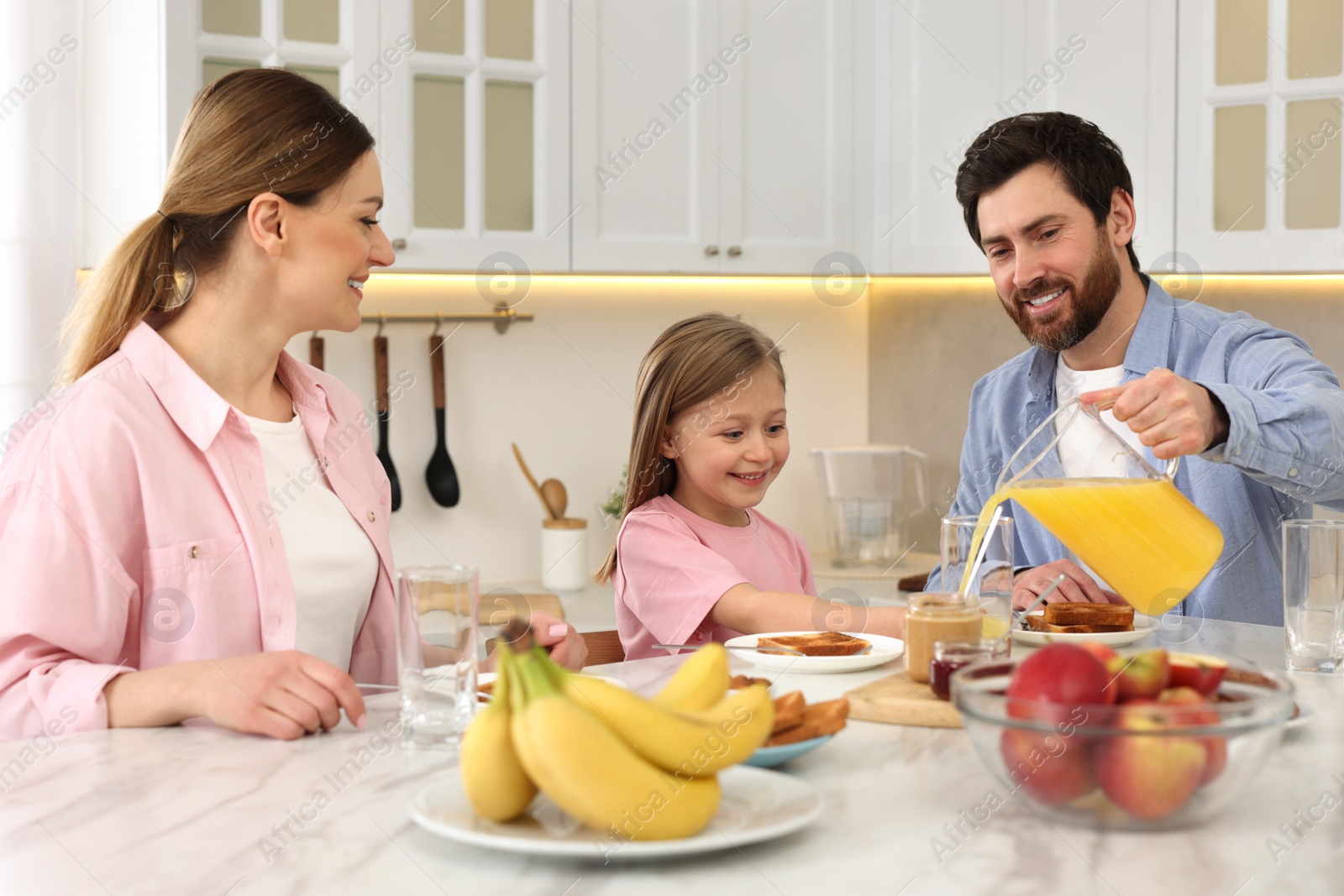 Photo of Happy family having breakfast at table in kitchen