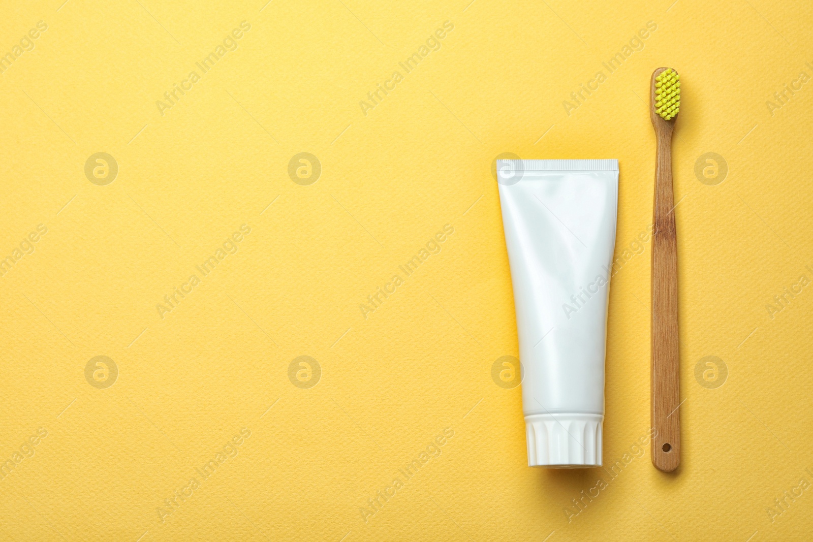 Photo of Blank tube of toothpaste and brush on color background, top view with space for text