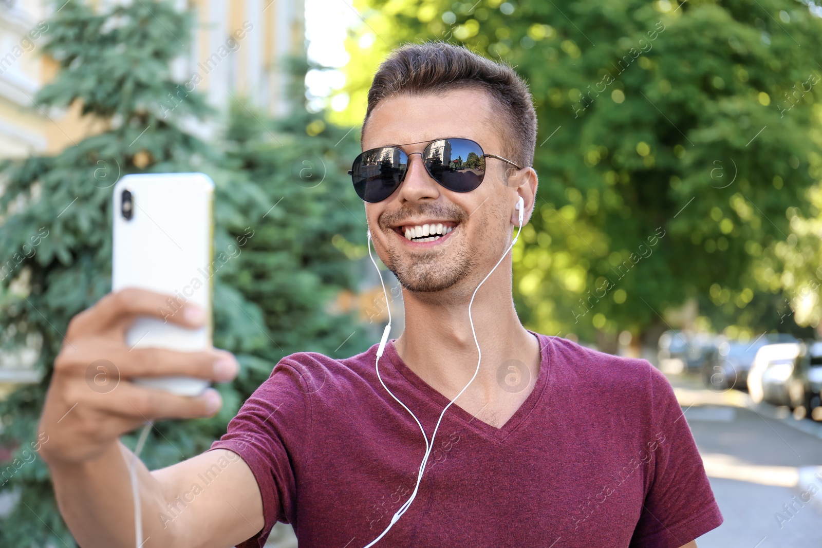 Photo of Young man in sunglasses taking selfie outdoors