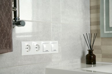 Photo of Light switches and power sockets on light grey wall in bathroom. Space for text