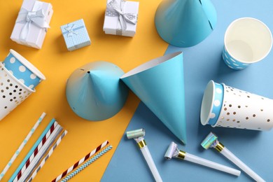 Party hats and other bright decor on color background, flat lay