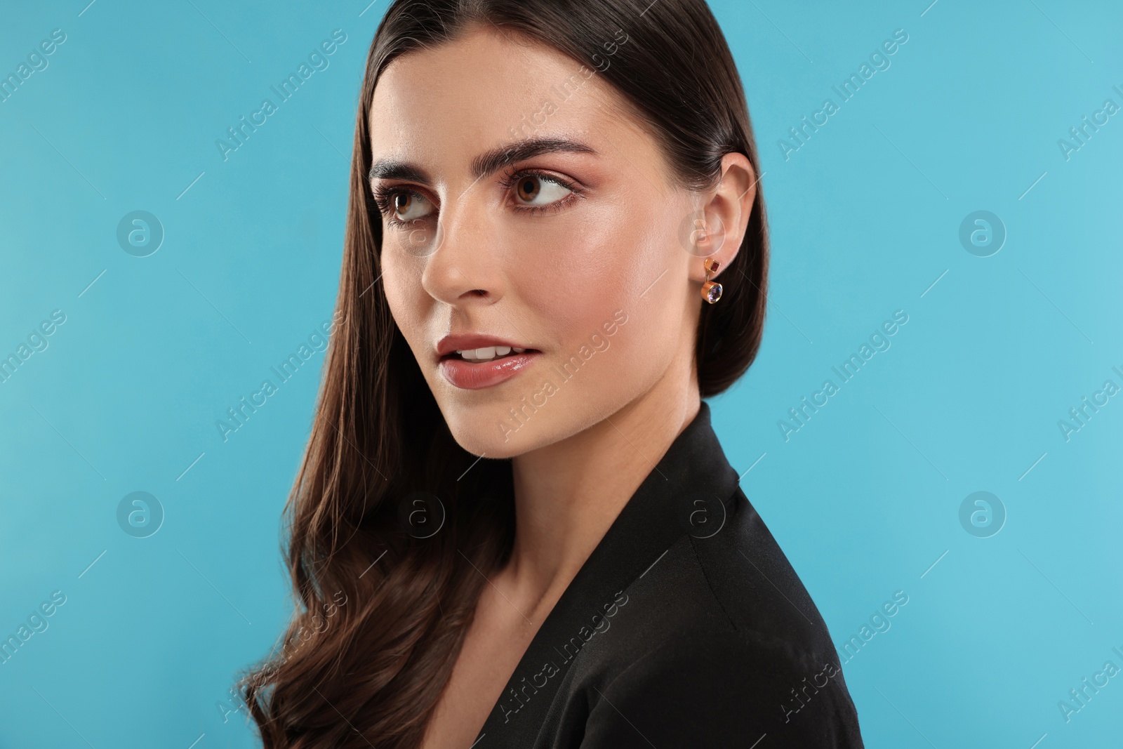 Photo of Beautiful woman with elegant earrings on light blue background