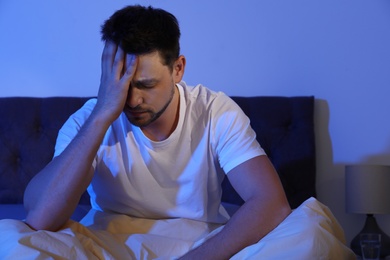 Sleepy handsome man sitting in dark room at night. Bedtime