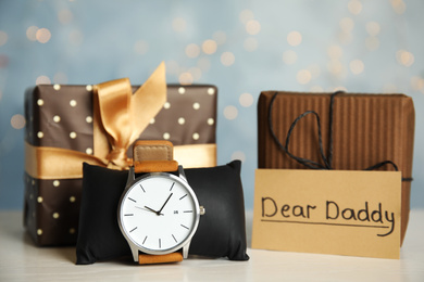 Photo of Composition with wristwatch and gift boxes on white table. Happy father's day