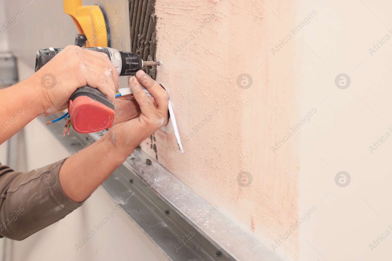 Photo of Worker installing socket in tile indoors, closeup