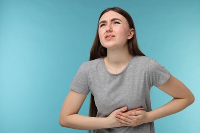 Woman having heart attack on light blue background