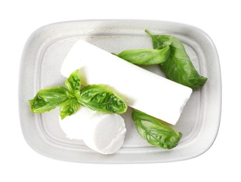 Delicious goat cheese with basil on white background, top view