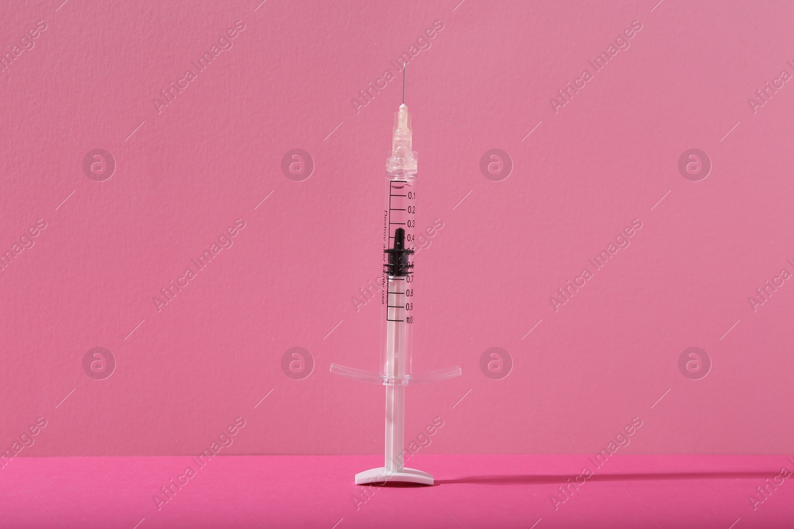 Photo of Cosmetology. One medical syringe on pink background