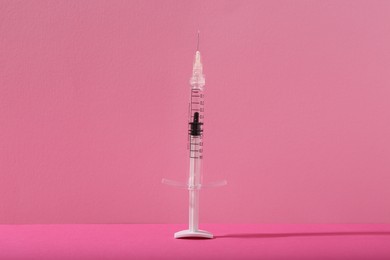Cosmetology. One medical syringe on pink background