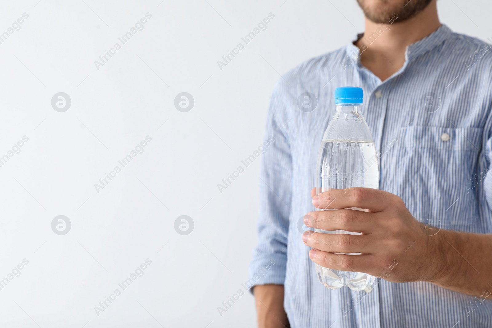 Photo of Man holding bottle of pure water on white background, closeup. Space for text