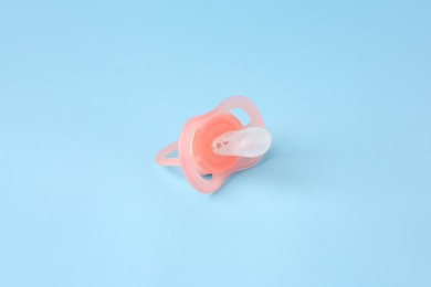 One new baby pacifier on light blue background