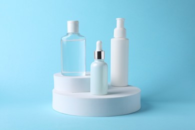Photo of Presentation of bottles with cosmetic serums on light blue background