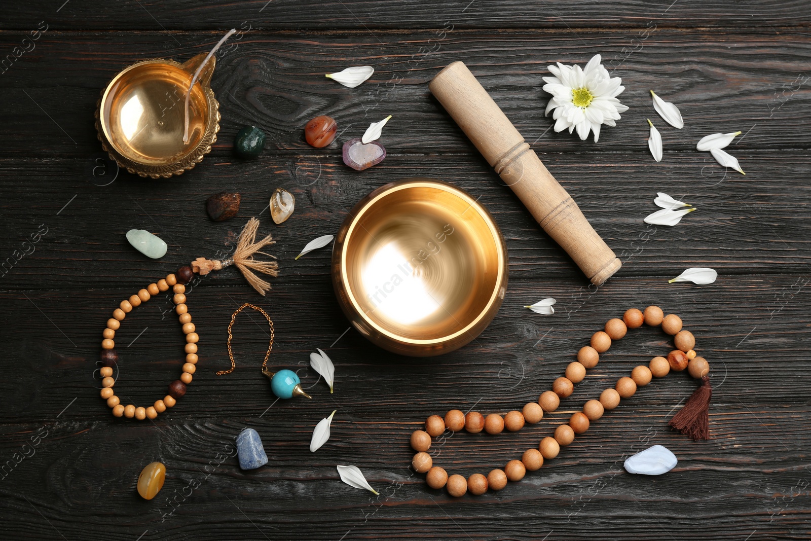 Photo of Flat lay composition with golden singing bowl on black wooden table. Sound healing