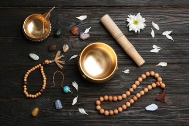 Flat lay composition with golden singing bowl on black wooden table. Sound healing