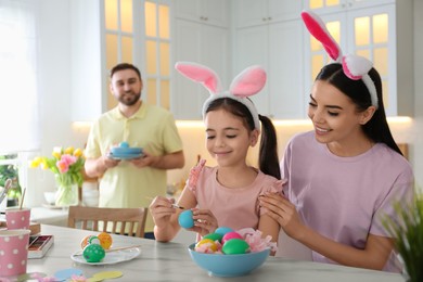 Photo of Happy family painting Easter eggs at table indoors