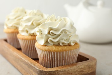 Photo of Tasty cupcakes with vanilla cream on light grey table, closeup