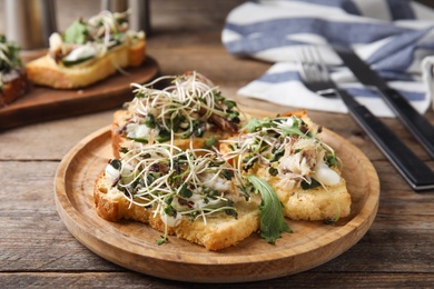 Photo of Delicious bruschettas with fish on wooden table