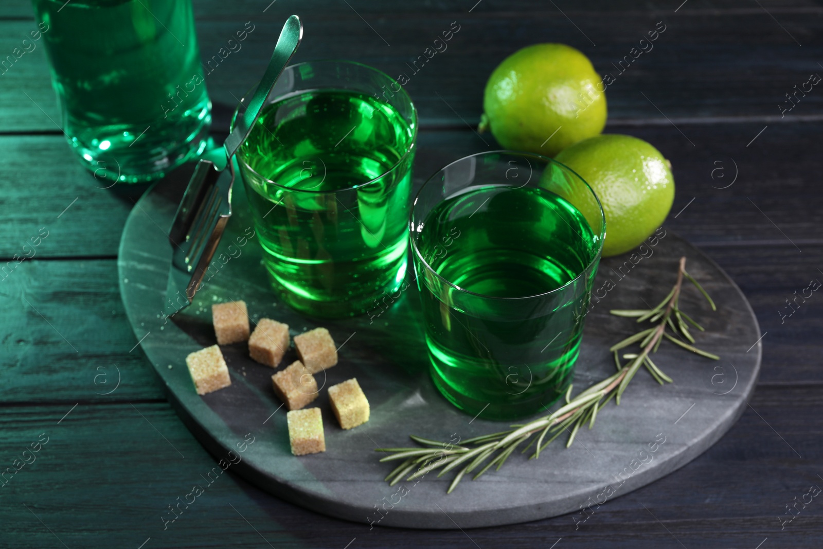 Photo of Absinthe in glasses, rosemary, brown sugar and lime on wooden table. Alcoholic drink