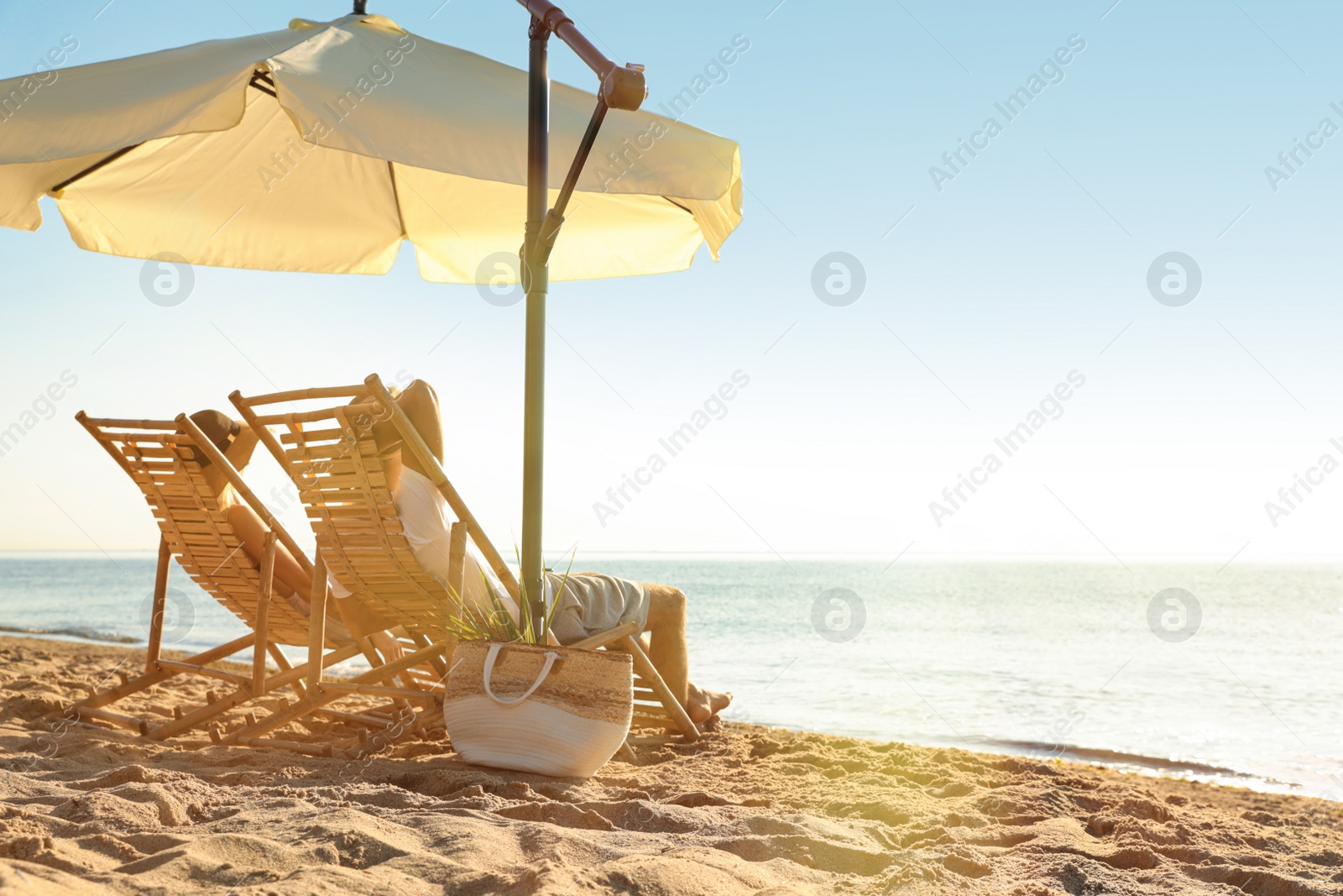 Photo of Couple relaxing on deck chairs at sandy beach. Summer vacation