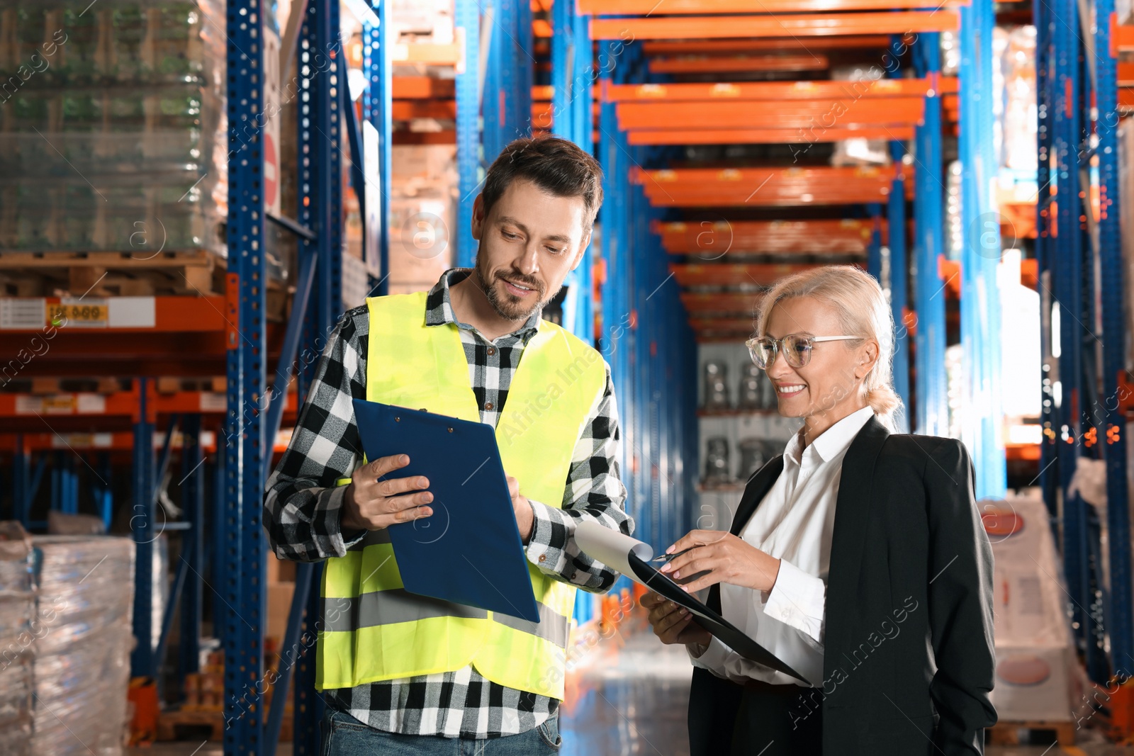 Photo of Manager and worker in warehouse with lots of products