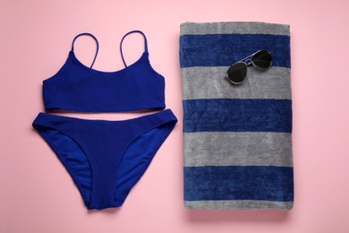 Beach towel, swimsuit and sunglasses on pink background, flat lay