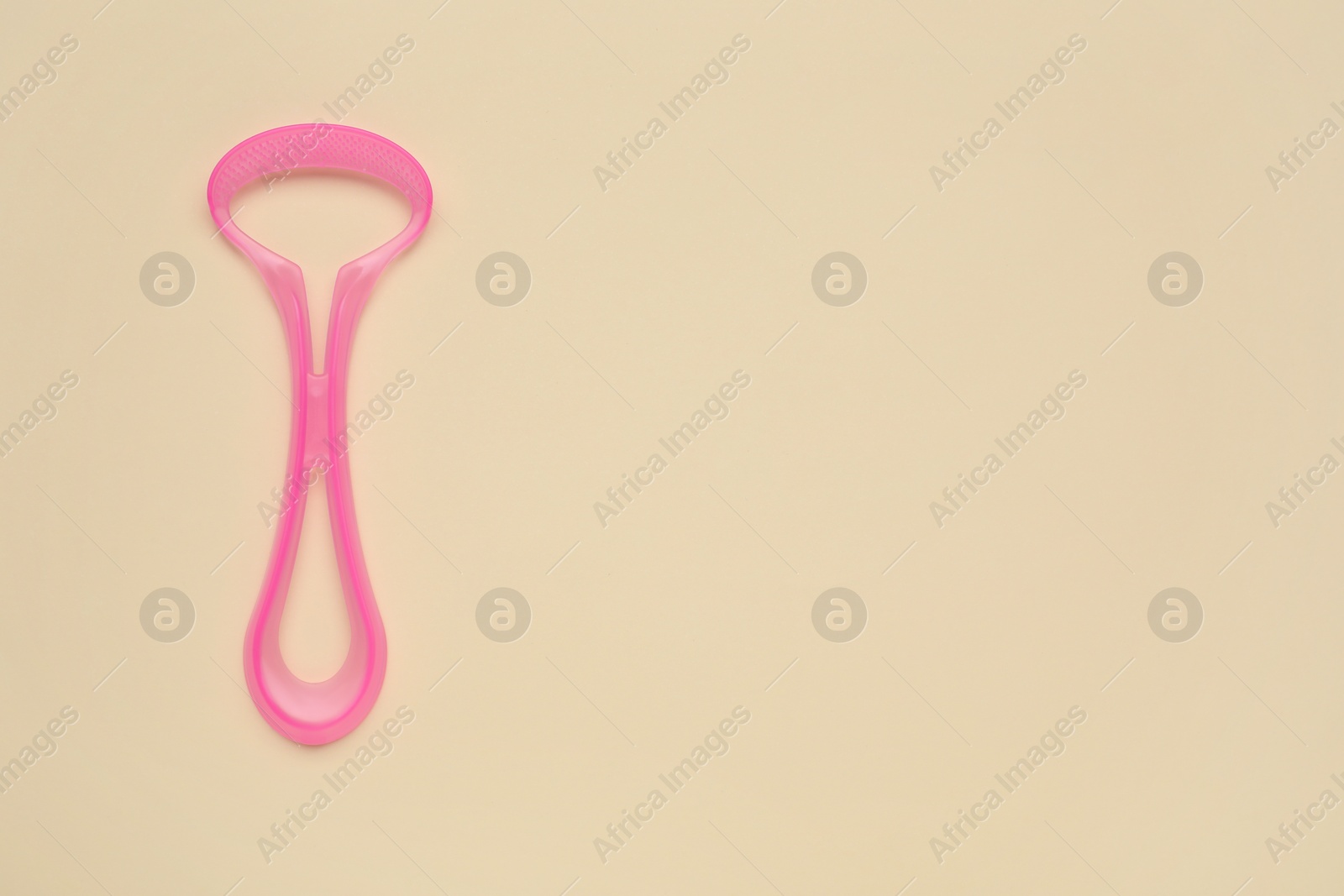 Photo of Pink tongue cleaner on beige background, top view. Space for text