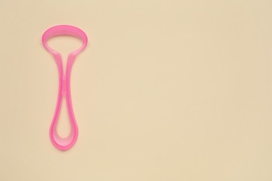 Photo of Pink tongue cleaner on beige background, top view. Space for text