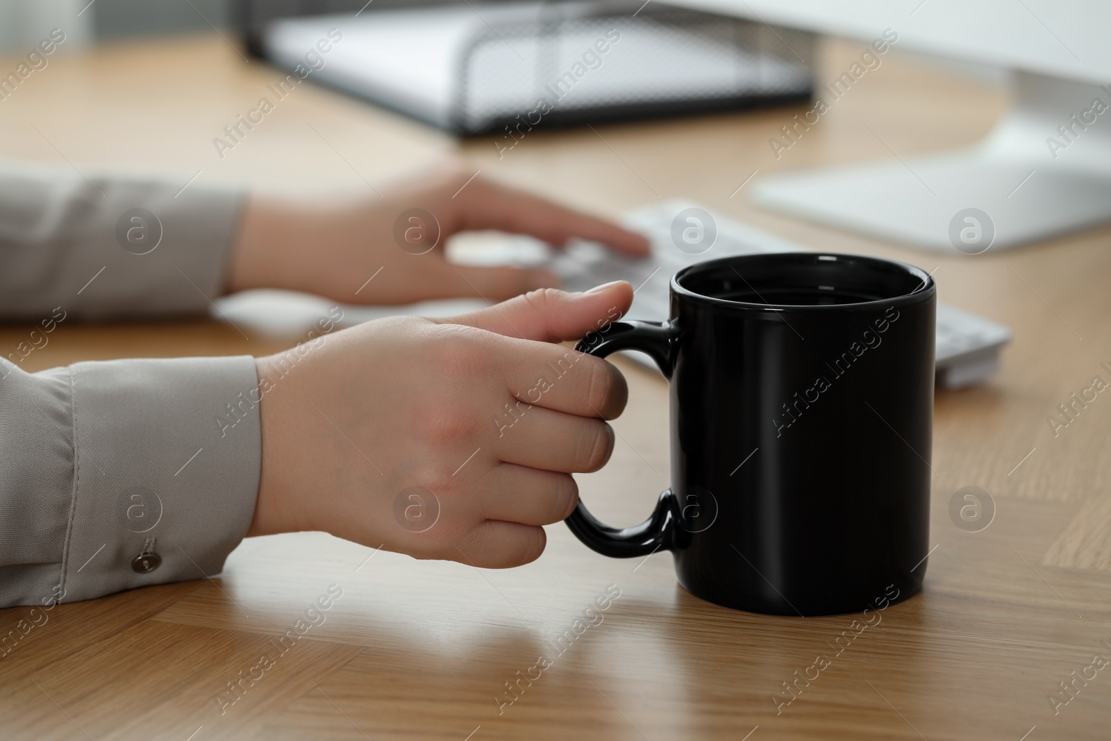 Photo of Woman with black ceramic mug at workplace, closeup