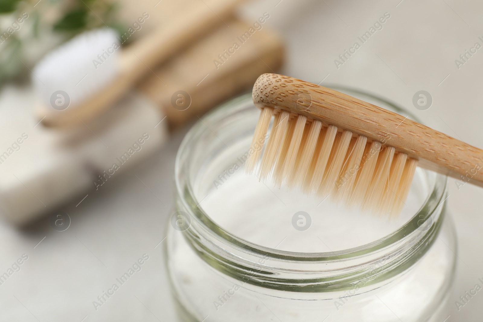 Photo of Bamboo toothbrush and jar of baking soda on table, closeup