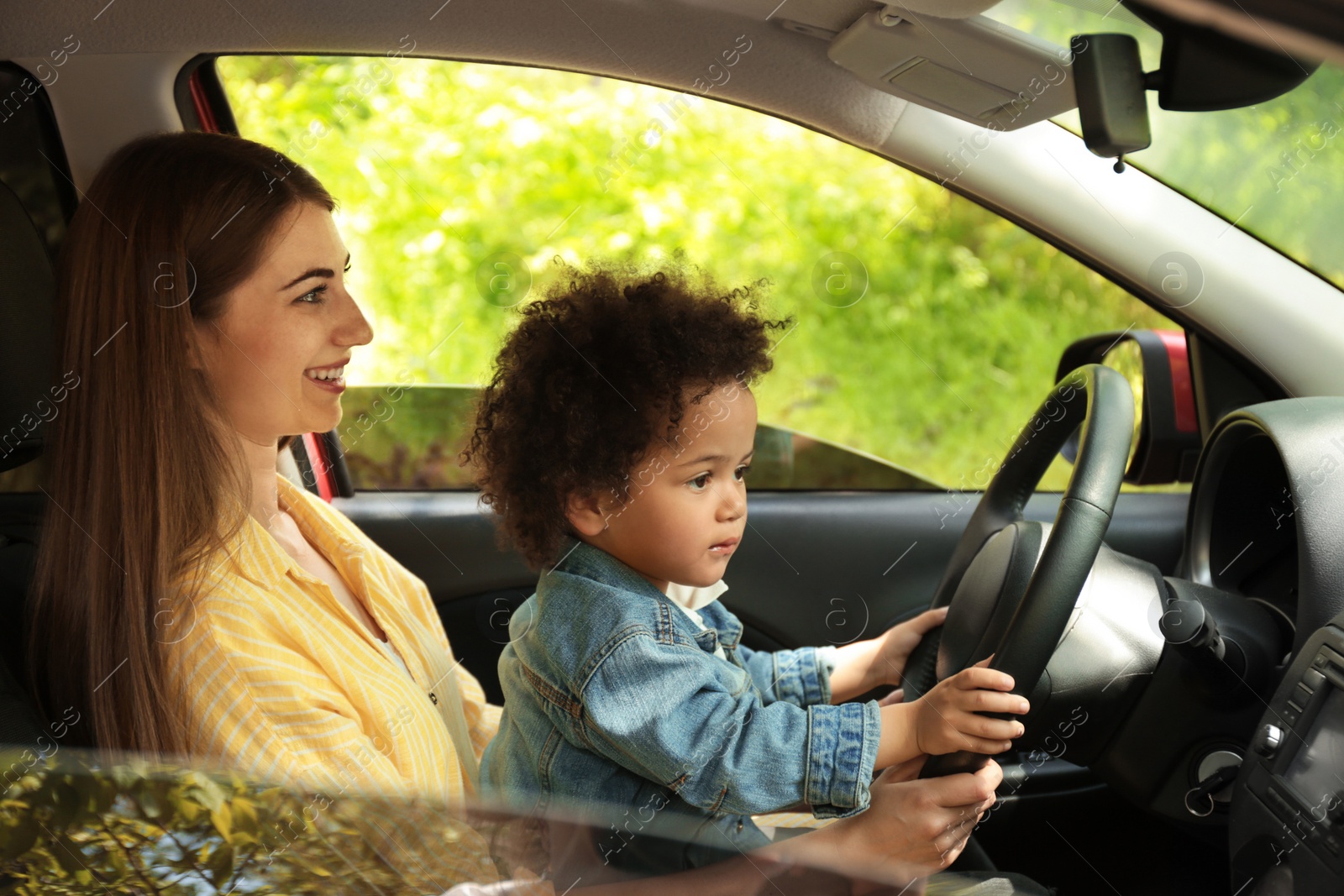 Photo of Mother with cute little daughter driving car together. Child in danger