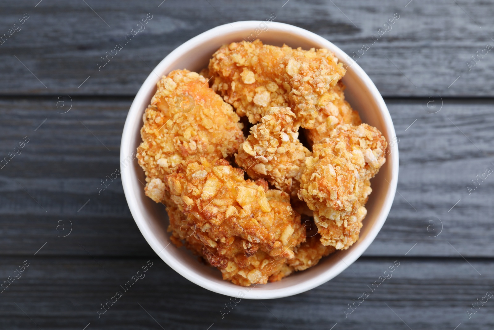 Photo of Bucket with yummy nuggets on dark wooden table, top view