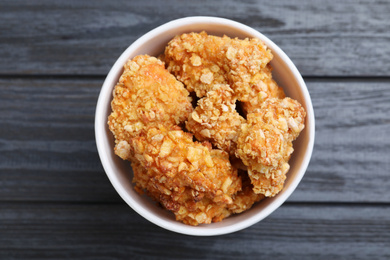 Bucket with yummy nuggets on dark wooden table, top view