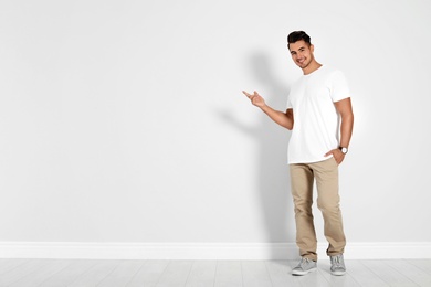 Photo of Full length portrait of handsome young man and space for text on white wall background