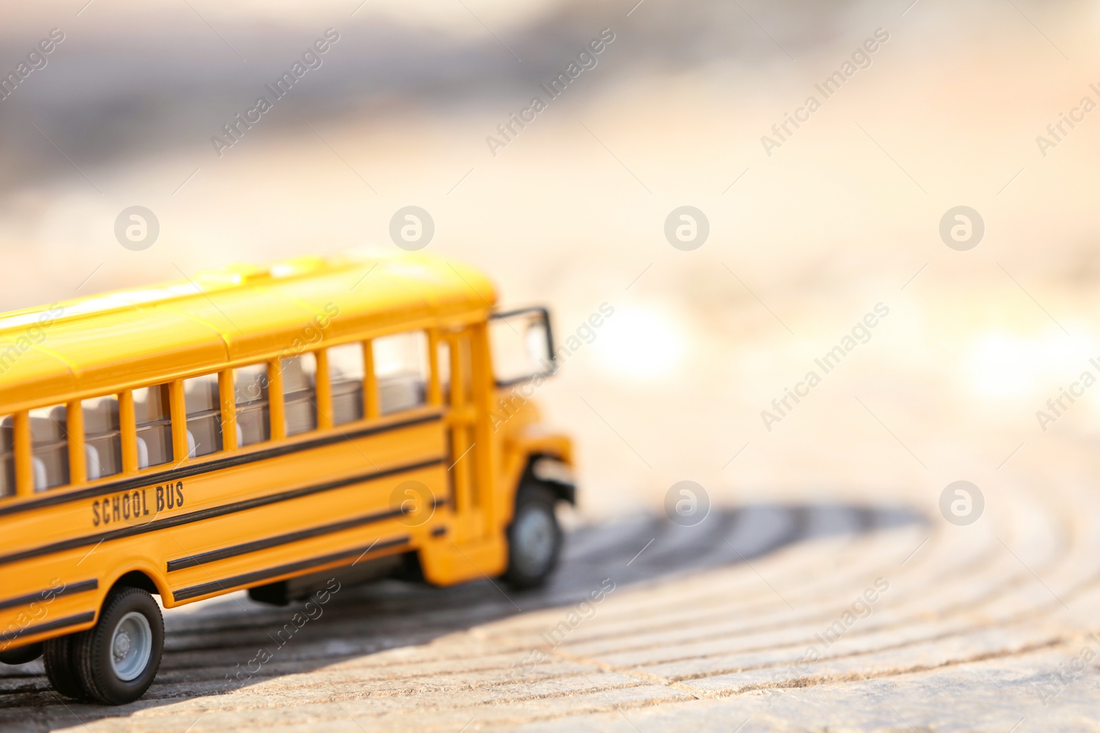 Photo of Yellow toy school bus outdoors on sunny day. Student's transport