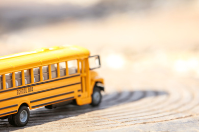 Photo of Yellow toy school bus outdoors on sunny day. Student's transport