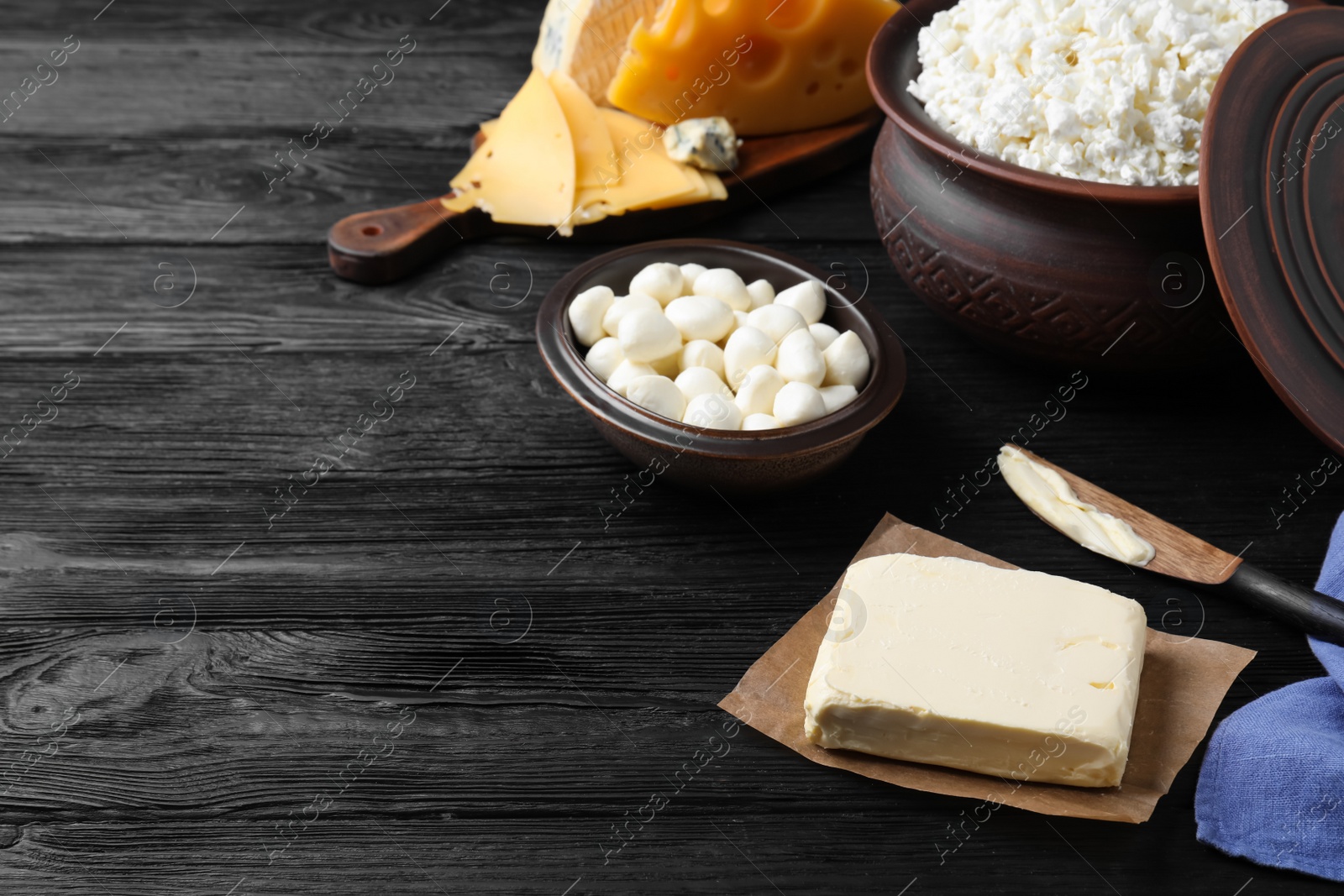 Photo of Clay dishware with fresh dairy products on black wooden table, space for text