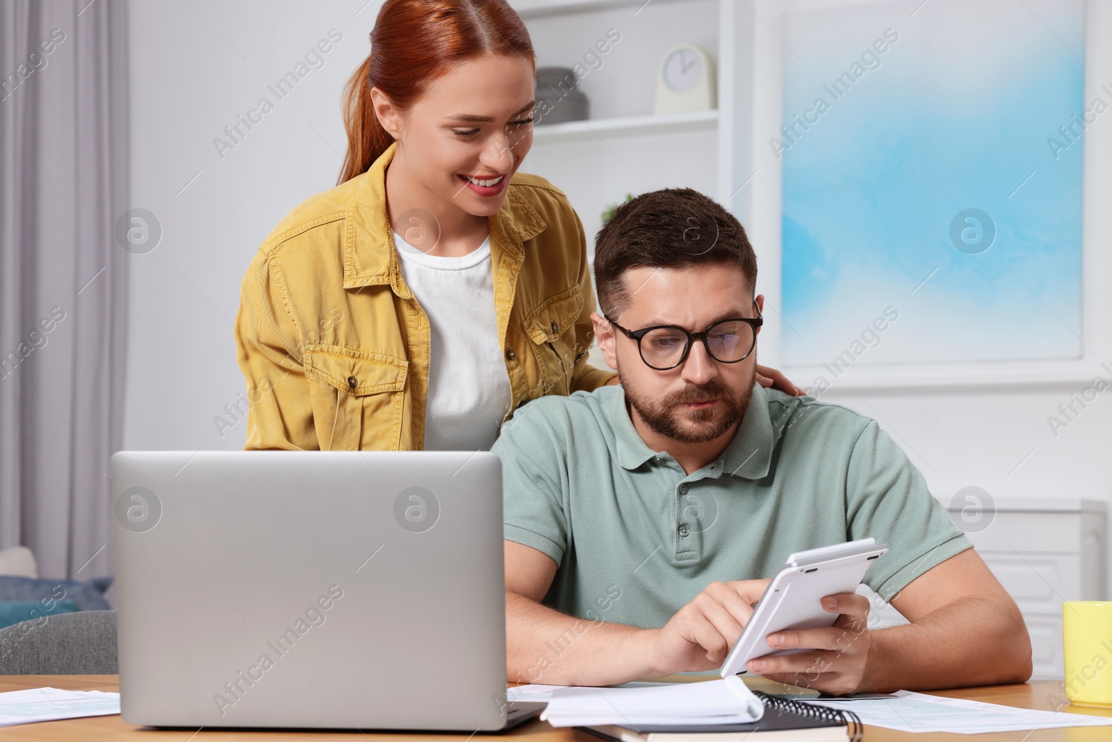 Photo of Couple calculating taxes for online payment at table in room