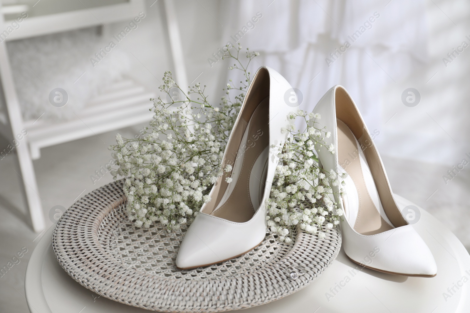 Photo of Beautiful wedding shoes, engagement ring and flowers on table indoors, closeup