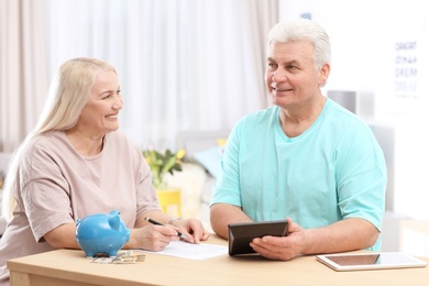 Mature couple thinking over pension payment at home