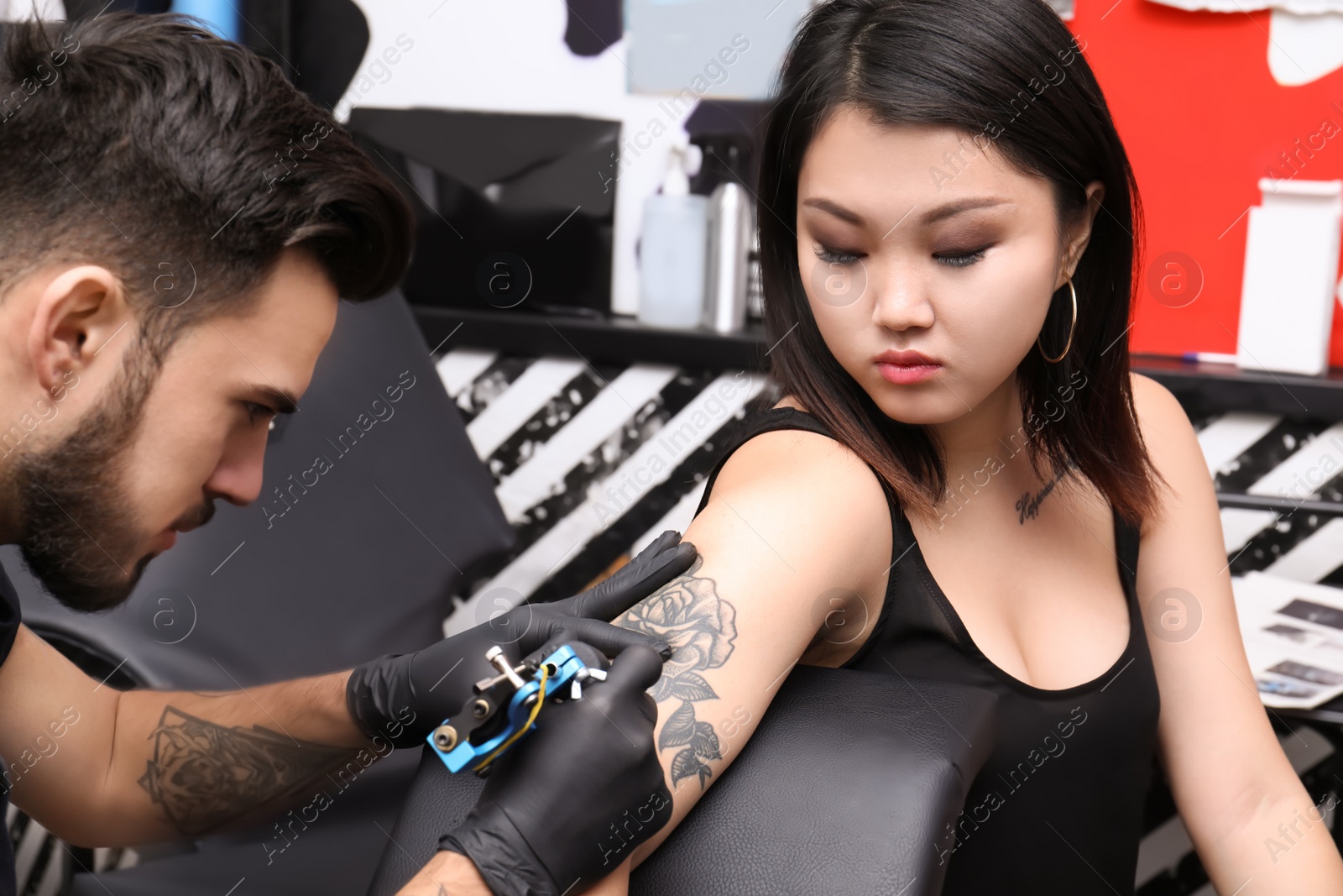 Photo of Professional artist making tattoo with machine in salon