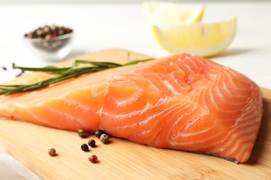 Photo of Wooden board with salmon fillet on table, closeup