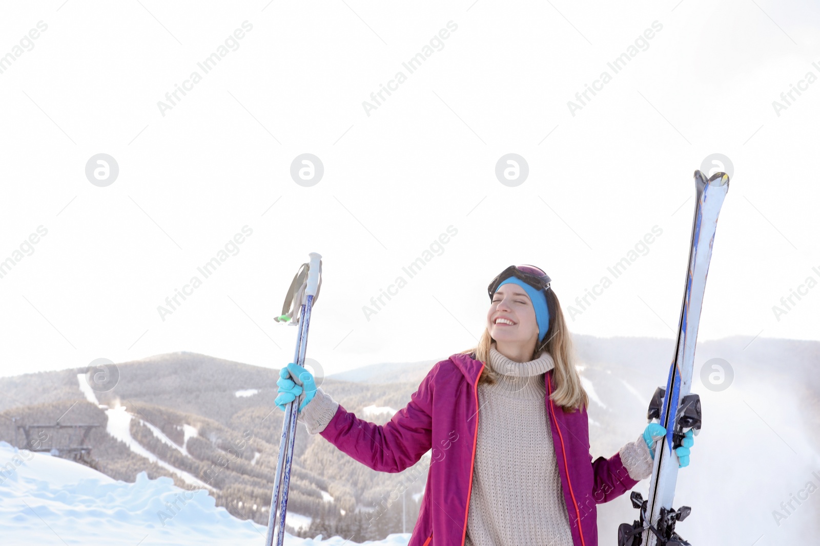 Photo of Happy young woman with ski equipment spending winter vacation in mountains. Space for text