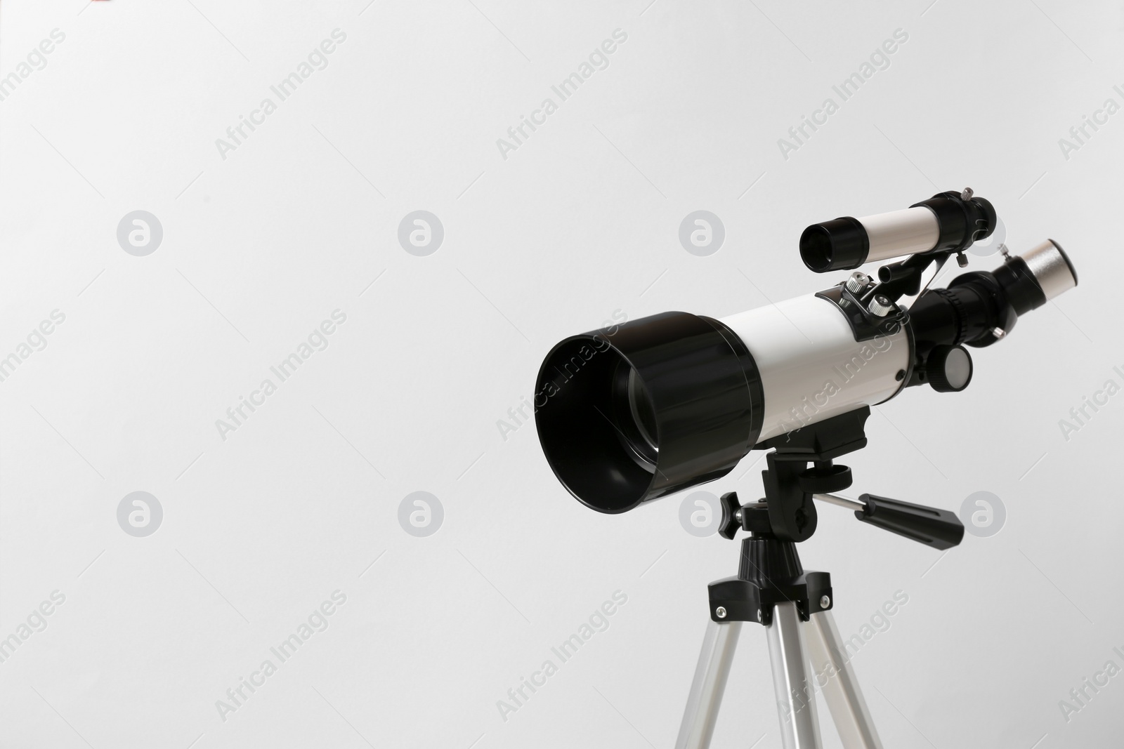 Photo of Tripod with modern telescope on light background, closeup. Space for text